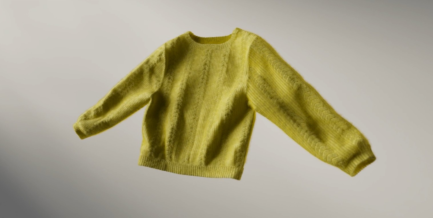 A chartreuse cable-knit sweater floating against a soft grey backdrop.